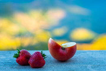 Strawberries and apples placed on a wooden background