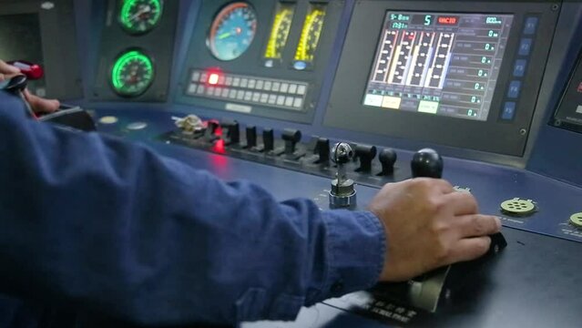 Train operator in blue uniform managing controls in locomotive cabin, dials and digital screens visible