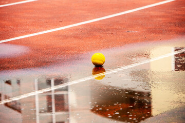 Close-up of a clay court ping ball inside the white line. A bright yellow ball on a clay court air...