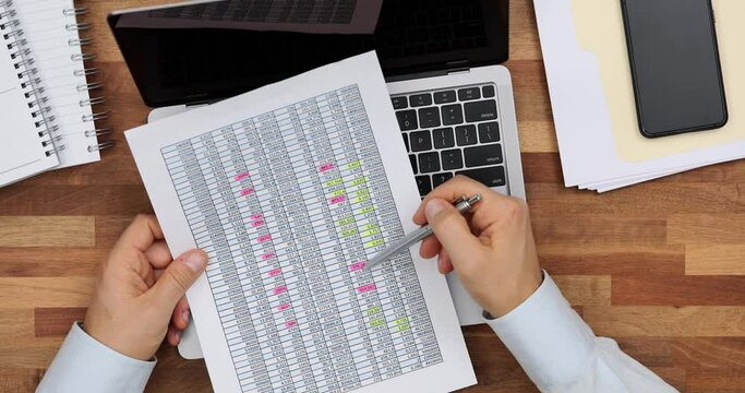 Worker compares data on paper sheet and on laptop at desk