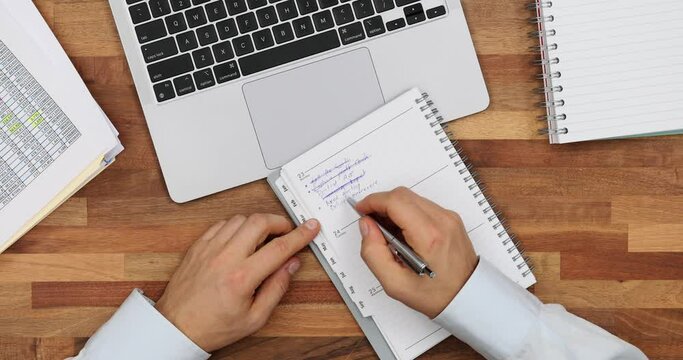 Manager crosses done tasks in plan list comparing at laptop