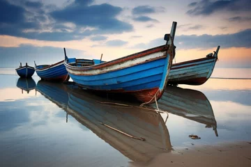 Fototapeten A peaceful reflection of a row of boats resting on a quiet beach © KerXing