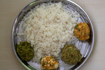 Traditional Bengali (Bangladeshi) food on a steel plate. White Rice with four kinds of Vorta like Aloo Bharta, Egg Bharta, Chepa Shutki Bharta, and Bean Bharta. Top view. 