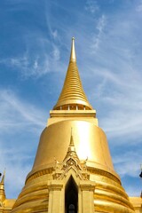 Naklejka premium Phra Si Rattana Chedi: a gold bell-shaped stupa at the Wat Phra Kaew (Temple of the Emerald Buddha) in Bangkok, housing relics of the Buddha from Sri Lanka, and covered in gold mosaic tiles