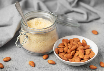Fresh almond flour in a  glass jar and almonds