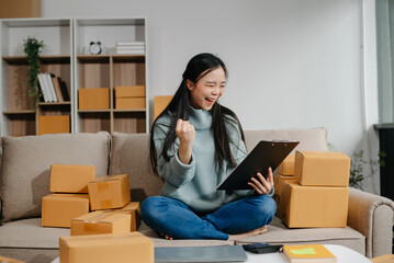 woman using smartphone or tablet taking receive and checking online purchase shopping order to preparing pack product box. .