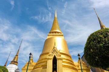 Naklejka premium Phra Si Rattana Chedi: a gold bell-shaped stupa at the Wat Phra Kaew (Temple of the Emerald Buddha), housing relics of the Buddha from Sri Lanka, and covered in gold mosaic tiles - Bangkok, Thailand