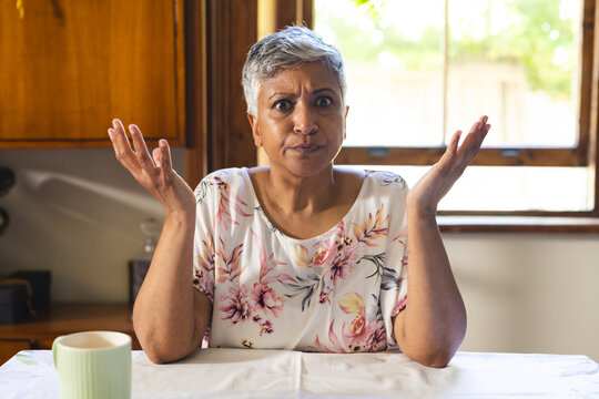 A mature biracial woman looks puzzled at home on a video call - Powered by Adobe