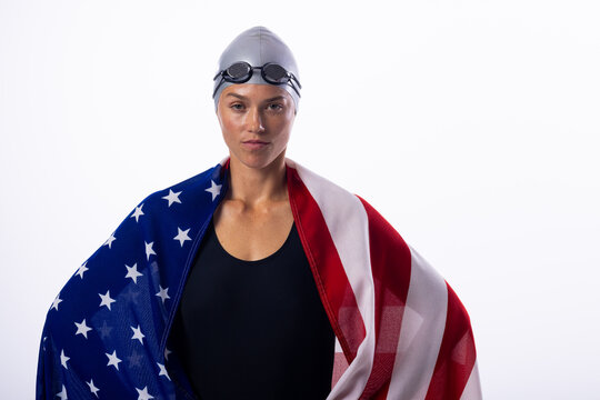 Female swimmer wrapped in the American flag stands confidently - Powered by Adobe