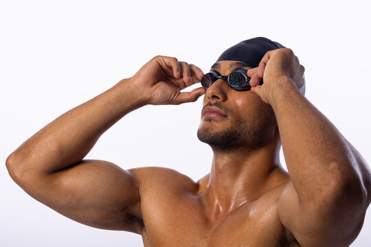 Young biracial male swimmer adjusts his swimming goggles