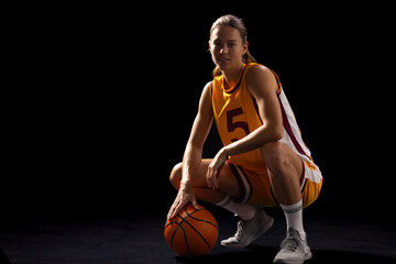 Young Caucasian female basketball player poses confidently in basketball attire, with copy space on 