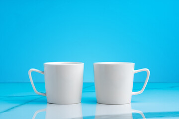 Two ceramic mugs on blue studio background