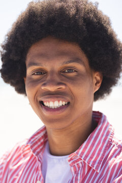 A young African American man smiles brightly at the beach