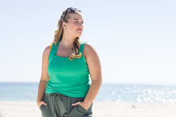 Naklejka premium Young plus-size Caucasian woman stands confidently on the beach, with copy space