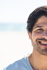 Fototapeta premium Young biracial man smiles brightly outdoors at the beach, with copy space
