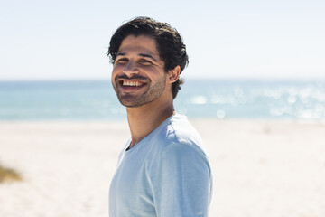 Fototapeta premium A young biracial man smiles brightly at the beach