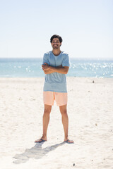 Young biracial man stands smiling on a sunny beach