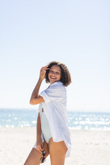 Fototapeta na wymiar Young biracial woman enjoys a sunny beach day, with copy space unaltered