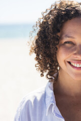 Fototapeta premium Young biracial woman smiles brightly at the beach
