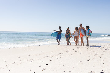 Diverse group of friends enjoy a beach day, with copy space