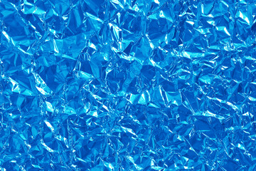Shiny blue foil texture background, pattern of wrapping paper with crumpled and wavy.