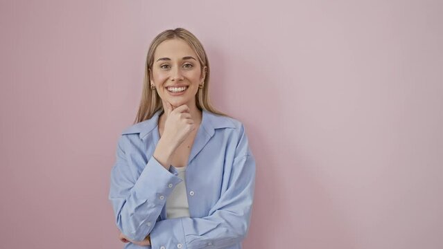 Confident blonde beauty, young woman in shirt, smiling with chin high and arms crossed, radiates positivity on isolated pink background. posing for the camera like a natural, proud superstar.