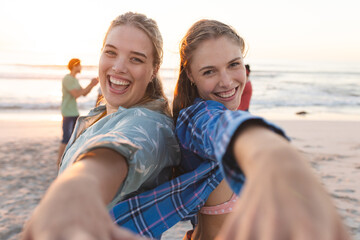 Fototapeta na wymiar Two young Caucasian women share a joyful moment on the beach