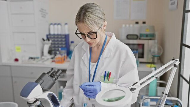 A focused woman scientist examining samples under a microscope in a modern laboratory setting.