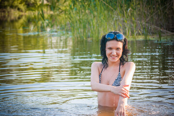 A girl with a beautiful body bathes in the river in summer.