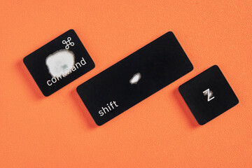 The command key, shift key and Z key are worn out due to frequent use and are removed from a keyboard with orange background