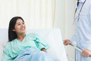 cheerful Asian doctor talking with young woman patient for monitoring and check up after surgery. doctor giving advice in the touchscreen to women to take care the lesion after out of hospital.