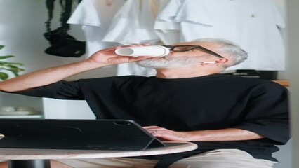 Working adult drink coffee at cafe vertical. Successful businessman look tablet