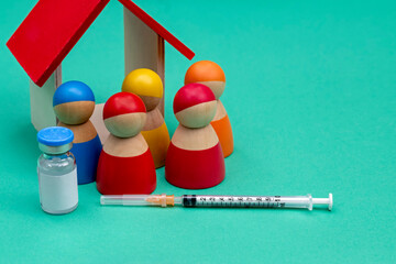 A needle and syringe with decoration of colorful wooden peg dolls, drug ampule and a toy house...