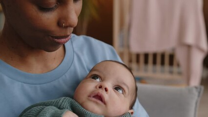 Medium closeup of rejoiced young Black woman holding baby son in arms and kissing him on tiny forehead