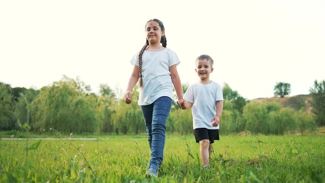 kids walk with pet dog on green grass in park at sunset.happy family kids have fun on grass on green lawn. Summer vacation picnic outdoors in park walking tour.Happy family and childhood dream concept