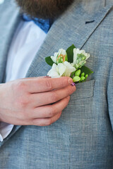 A boutonniere of fresh flowers on a man's jacket. A wedding or engagement.