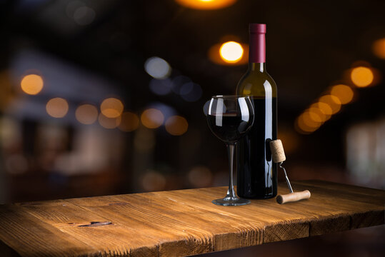 Bottle and glass of red wine on a red background. Copy space for your text. High quality photo