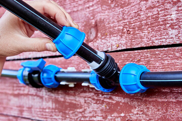 An external water supply system connected by compression fittings is mounted on weathered wall of...