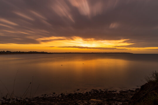A spectacular sunrise over the ocean, on an autumn morning, under a cloudy sky. Long exposure.