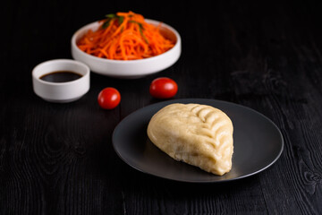 Korean food. Pigody with sauce and carrots on a black wooden background