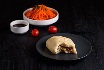 Korean food. Pigody with sauce and carrots on a black wooden background