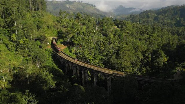 A passenger train passes the old colonial railway bridge in the mountain jungle of Sri Lanka.