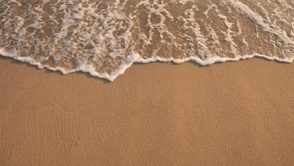 Fototapeta na wymiar White foamy background of waves crashing on a sandy beach.