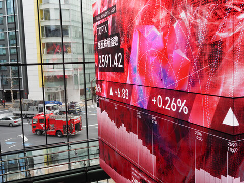 TOKYO, JAPAN - February 15, 2024: Screens on blocks display financial information including TOPIX in Tokyo's Kabuto One building.  There's a fire engine, crane truck etc. on the road outside.