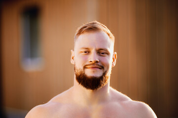 Grinning bearded face of white male in his 30s outdoors.