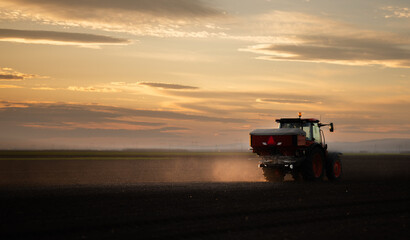 Tractor spreading artificial fertilizers in field