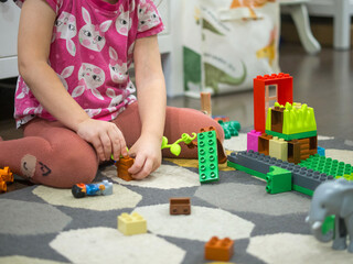 girl plays with construction kit at home on the floor, collect construction kit