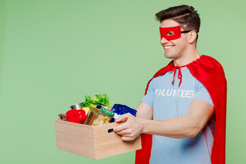 Young man wears blue t-shirt white title volunteer super hero costume hold box with groceries food...