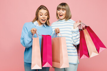 Elder happy parent mom with young adult daughter two women together wear blue casual clothes hold open package bags after shopping isolated on plain pink background. Black Friday sale buy day concept.