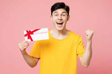 Young surprised Caucasian man wear yellow t-shirt casual clothes hold gift certificate coupon...